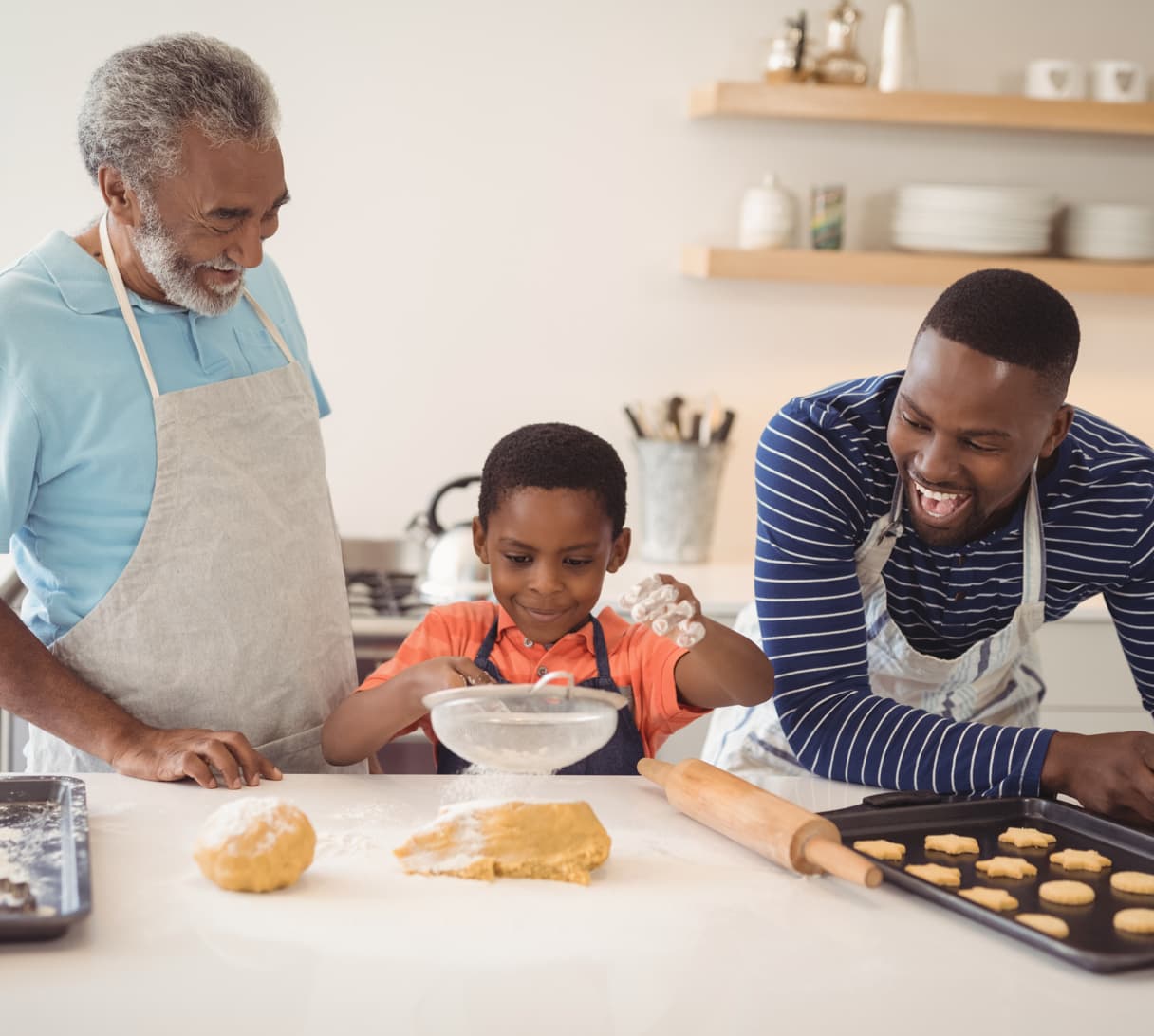 Grandfather, father, and son baking cookies in a kitchen.