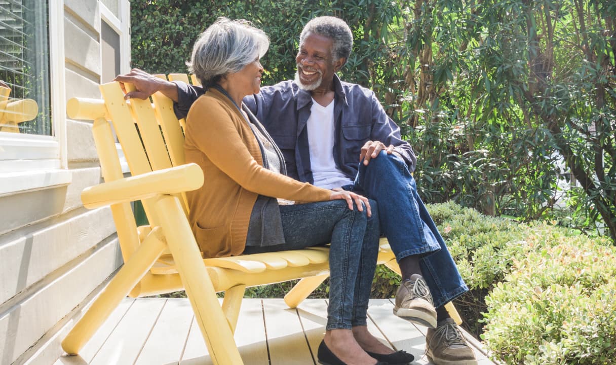 A couple sits on a front porch bench
